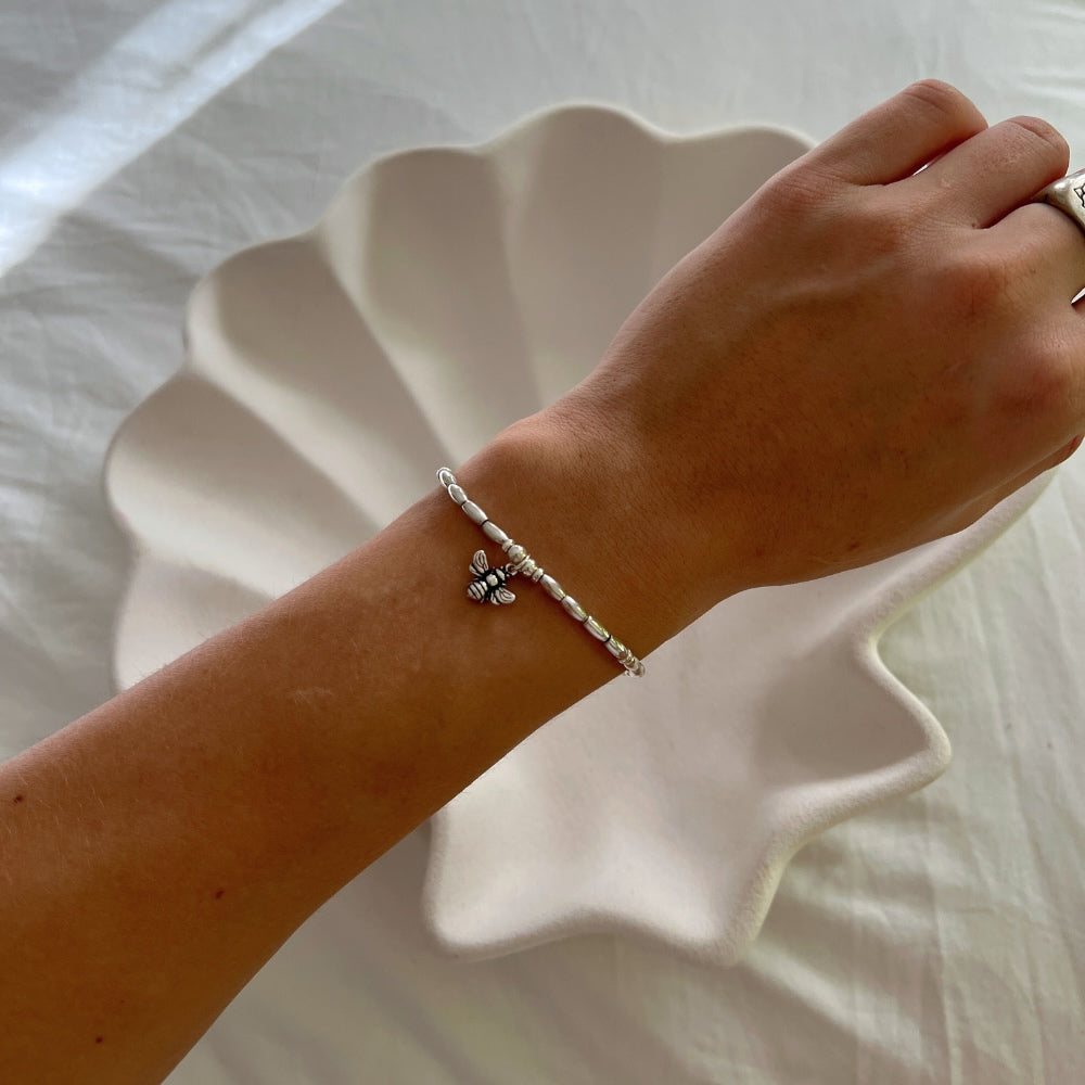 Embrace the beauty and energy of nature with our Bee Charm Sterling Silver Beaded Bracelet. Handcrafted with sterling silver beads on a durable wax string, this bracelet showcases a charming bee motif at its center. Perfect for adding a touch of whimsy and elegance to any outfit. Buzz into style with this charming bracelet!