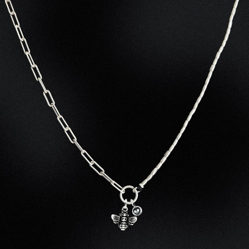 Silver chain necklace with a bee pendant on a black background