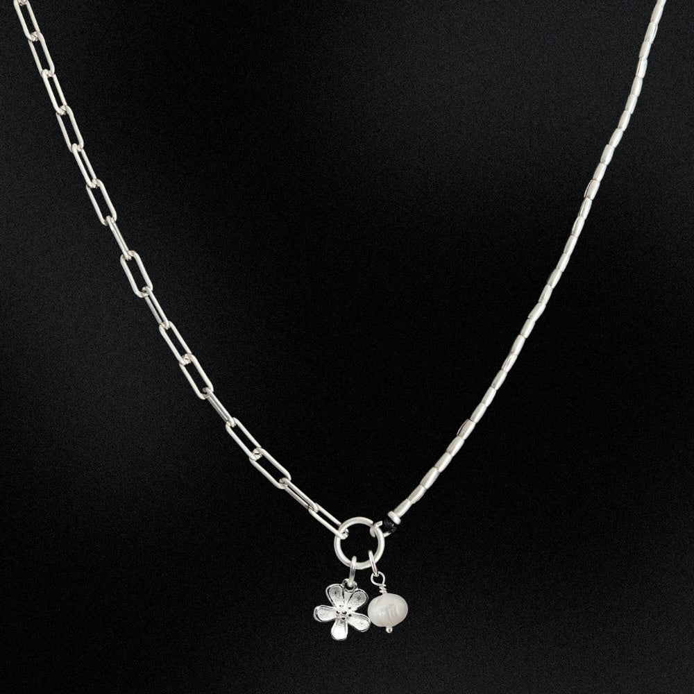 Silver necklace with a floral pendant on a black background