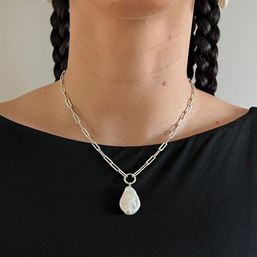 Necklace with a teardrop pendant worn by a person against a neutral background