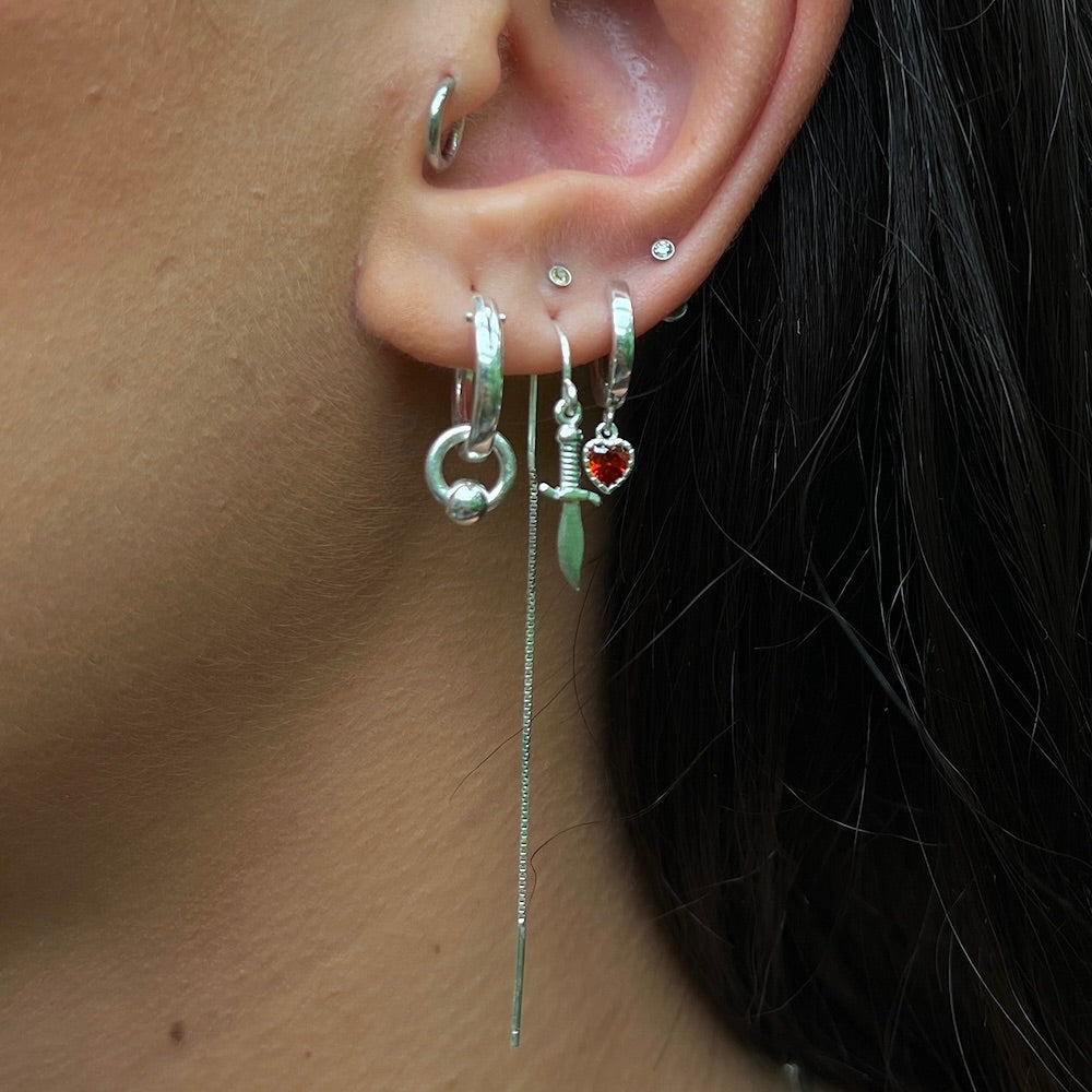Close-up of an ear with multiple silver earrings on a blurred background