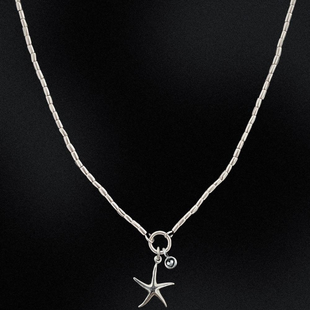 Silver necklace with a starfish pendant on a black background