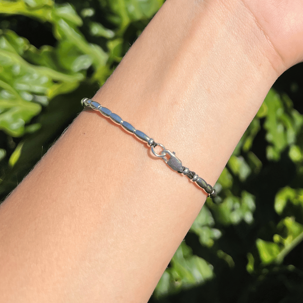 Introducing the Midnight Essence Silver Beaded Bracelet - the perfect accessory to complete any outfit. The centre detail of the bracelet features stunning faceted glass rondelle black beads that catch the light and sparkle brilliantly. Surrounding these gems are delicate silver beads, adding a touch of sophistication and elegance to the design.