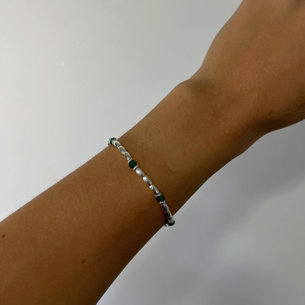 Introducing the Emerald Essence Silver Beaded Bracelet - the perfect accessory to complete any outfit. The centre detail of the bracelet features stunning faceted glass rondelle green beads that catch the light and sparkle brilliantly. Surrounding these gems are delicate silver beads, adding a touch of sophistication and elegance to the design.