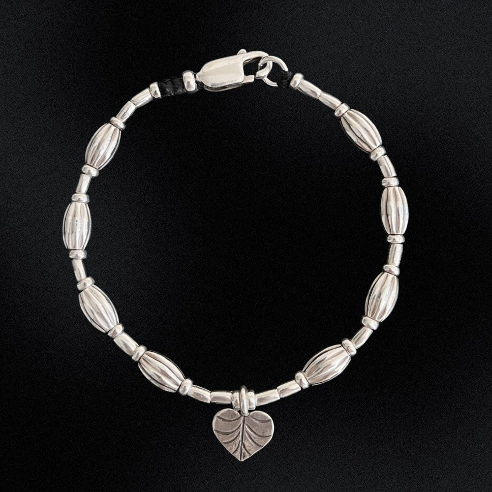 A true work of art. Handcrafted with intricate detail, this bracelet features a heart leaf charm at its centrepiece that is sure to capture your heart. The charm is complemented by corrugated beads that add a textural element to the bracelet.  Crafted from high-quality Hill Tribe Silver, the delicate balance of the charm and the beads brings together a perfect harmony of nature and artistry that is sure to make you stand out from the crowd.