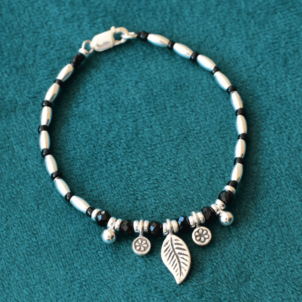The Leafy Midnight Bloom Beaded Bracelet is not only a stunning piece of jewellery, but it is also a meaningful and symbolic addition to your collection. The leaf charm represents growth and transformation, while the daisy charms are a symbol of innocence and purity. Made with high-quality sterling silver, the bracelet features a classic black and silver colour combination that's sure to complement any outfit.