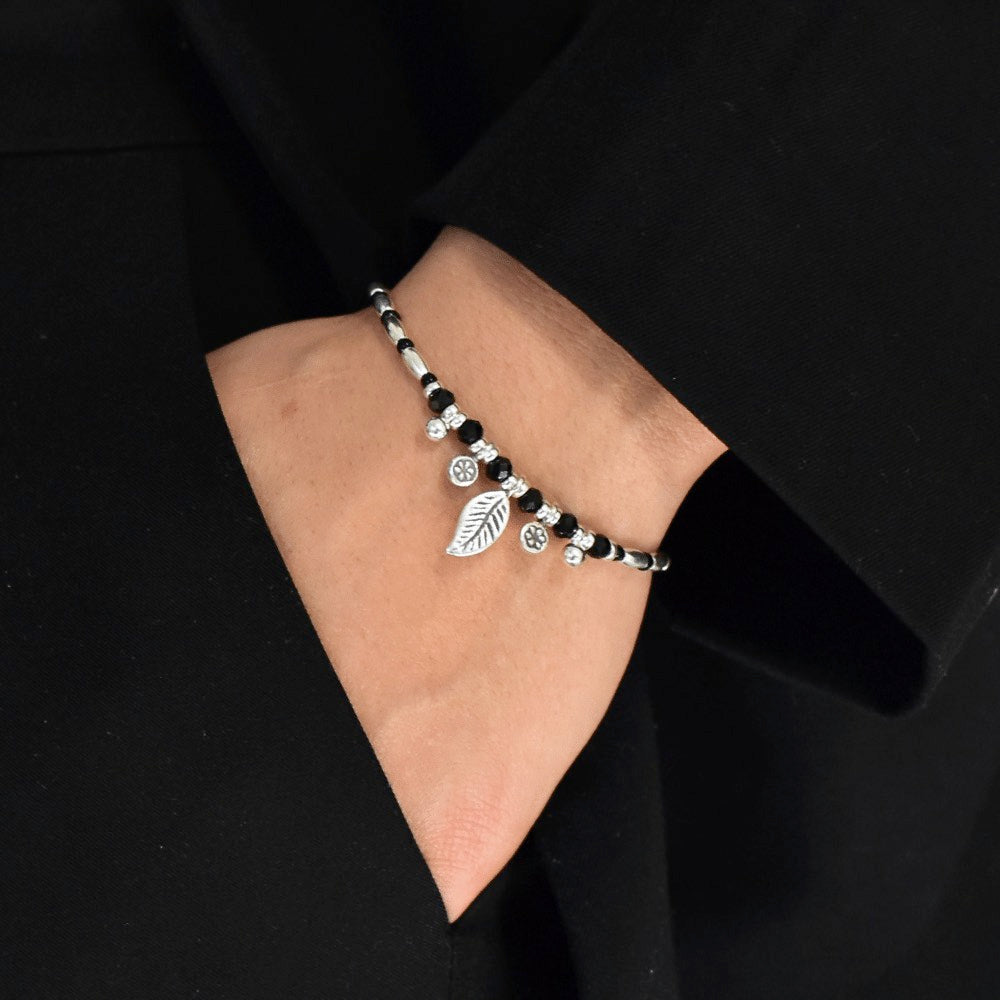 The Leafy Midnight Bloom Beaded Bracelet is not only a stunning piece of jewellery, but it is also a meaningful and symbolic addition to your collection. The leaf charm represents growth and transformation, while the daisy charms are a symbol of innocence and purity. Made with high-quality sterling silver, the bracelet features a classic black and silver colour combination that's sure to complement any outfit.