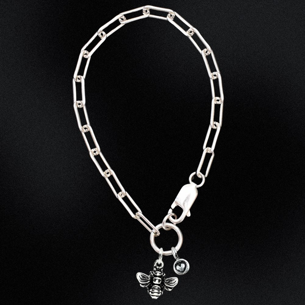 Silver chain bracelet with a bee charm on a black background
