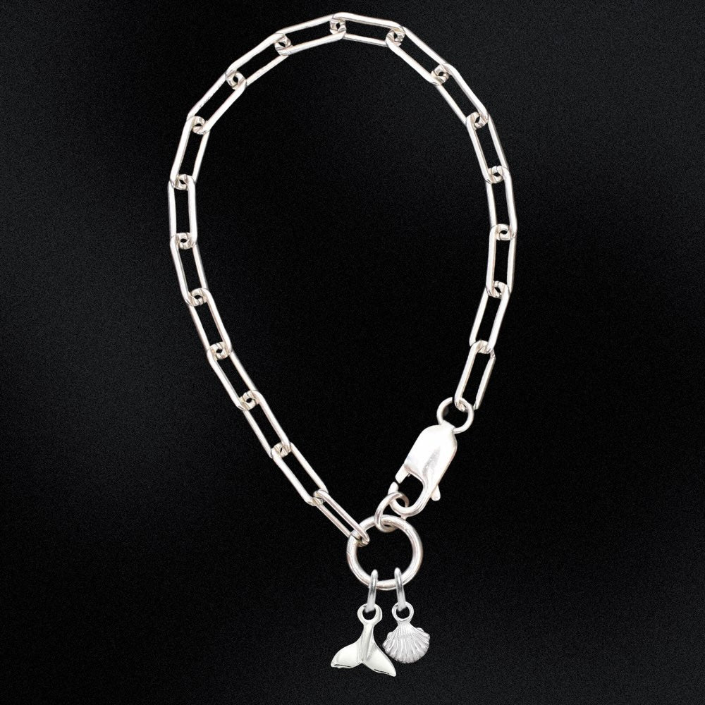 Silver chain bracelet with a fish charm on a black background