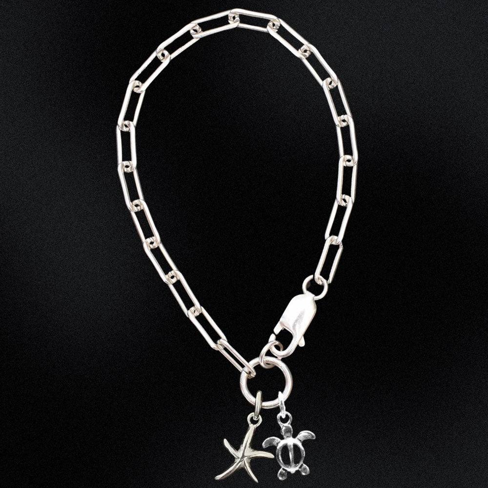 Silver chain bracelet with starfish and turtle charms on a black background