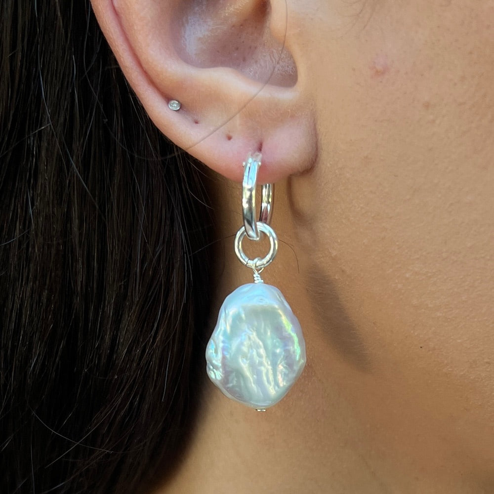 Pearl earring on a person's ear with a close-up view