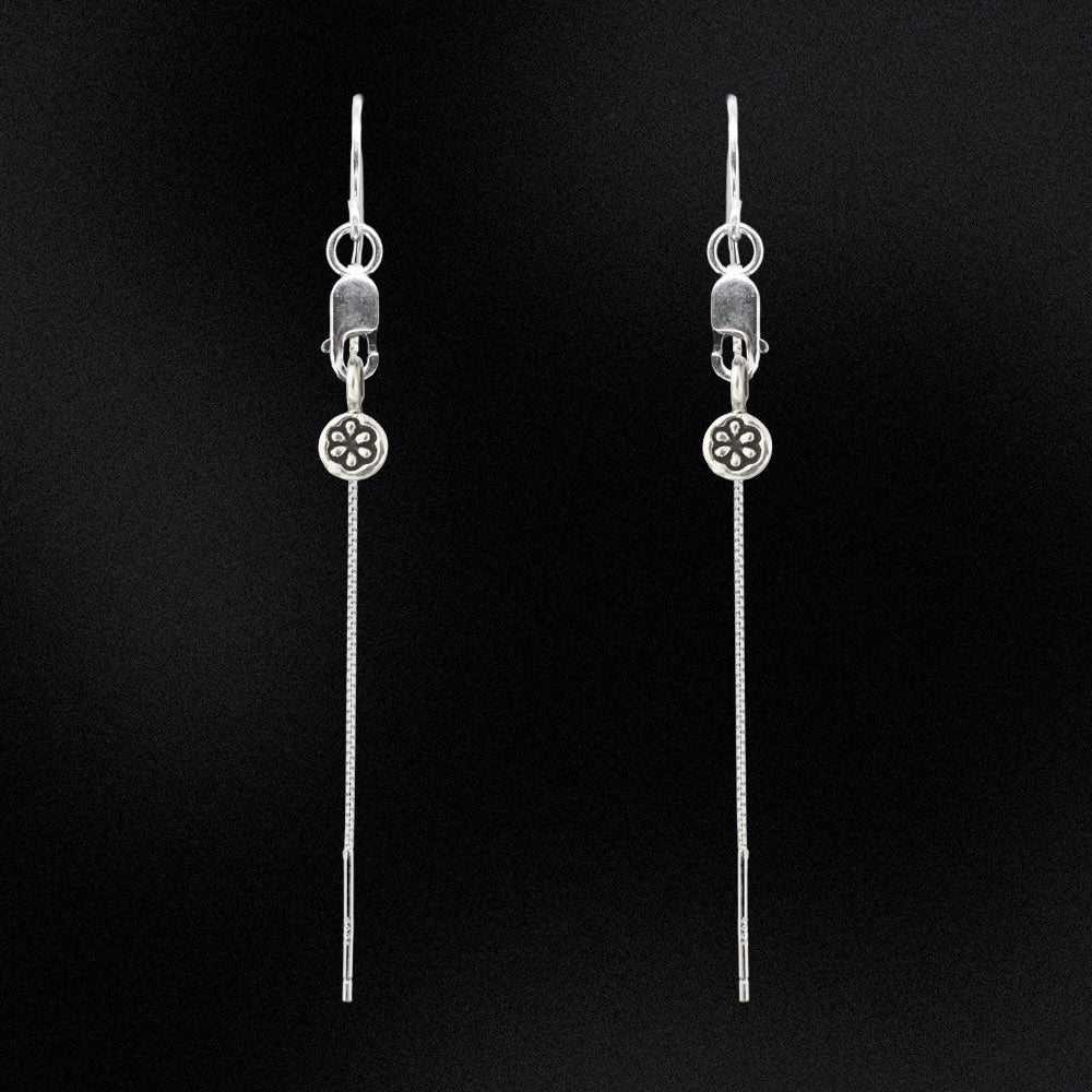 Pair of silver threader earrings on a black background