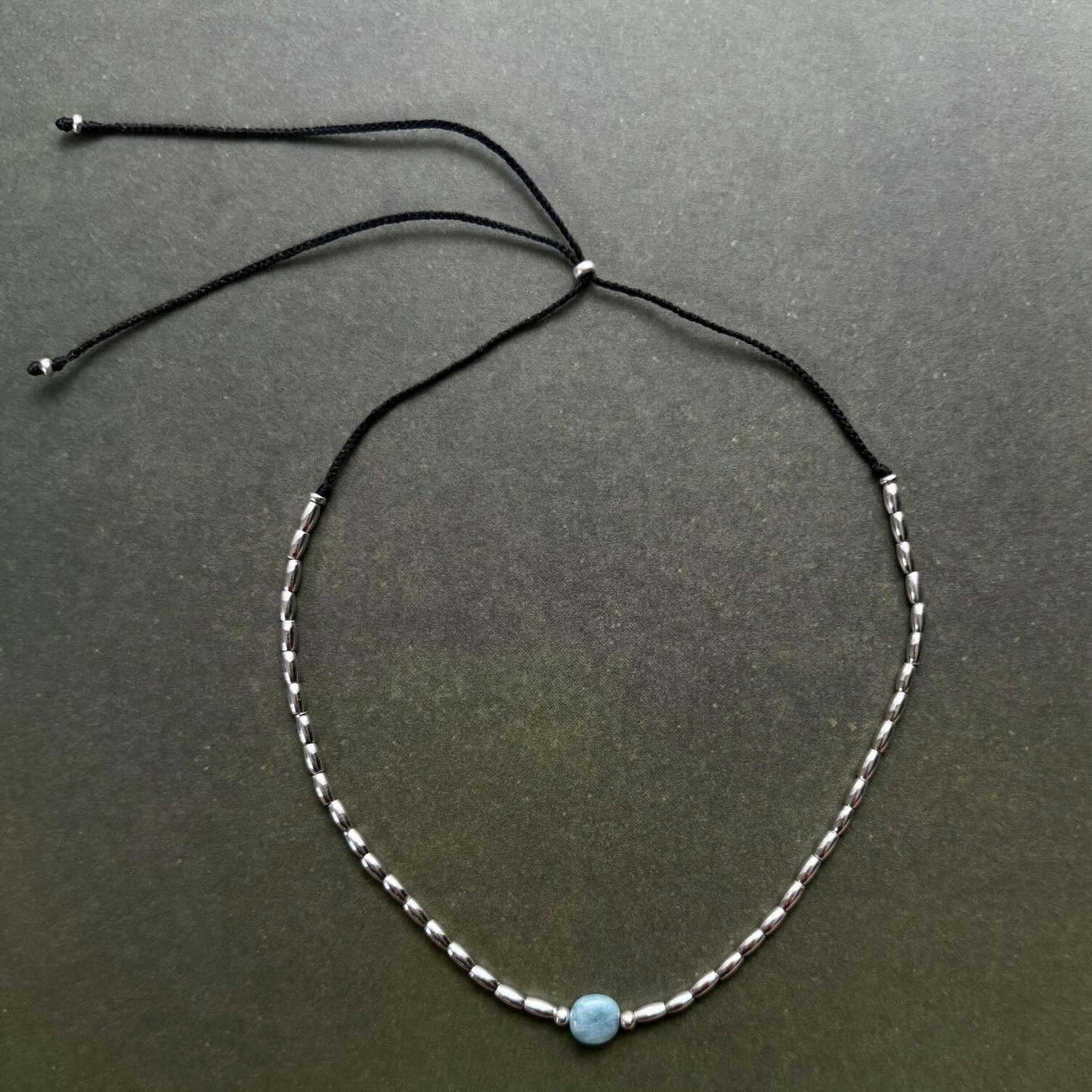 Necklace with a blue bead on a dark gray background