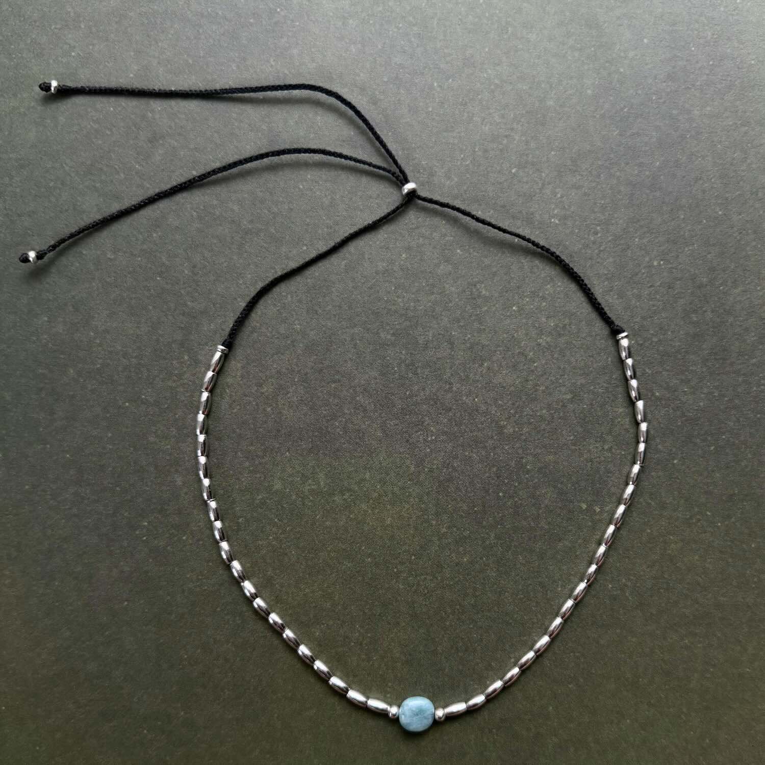 Necklace with a blue bead on a dark gray background