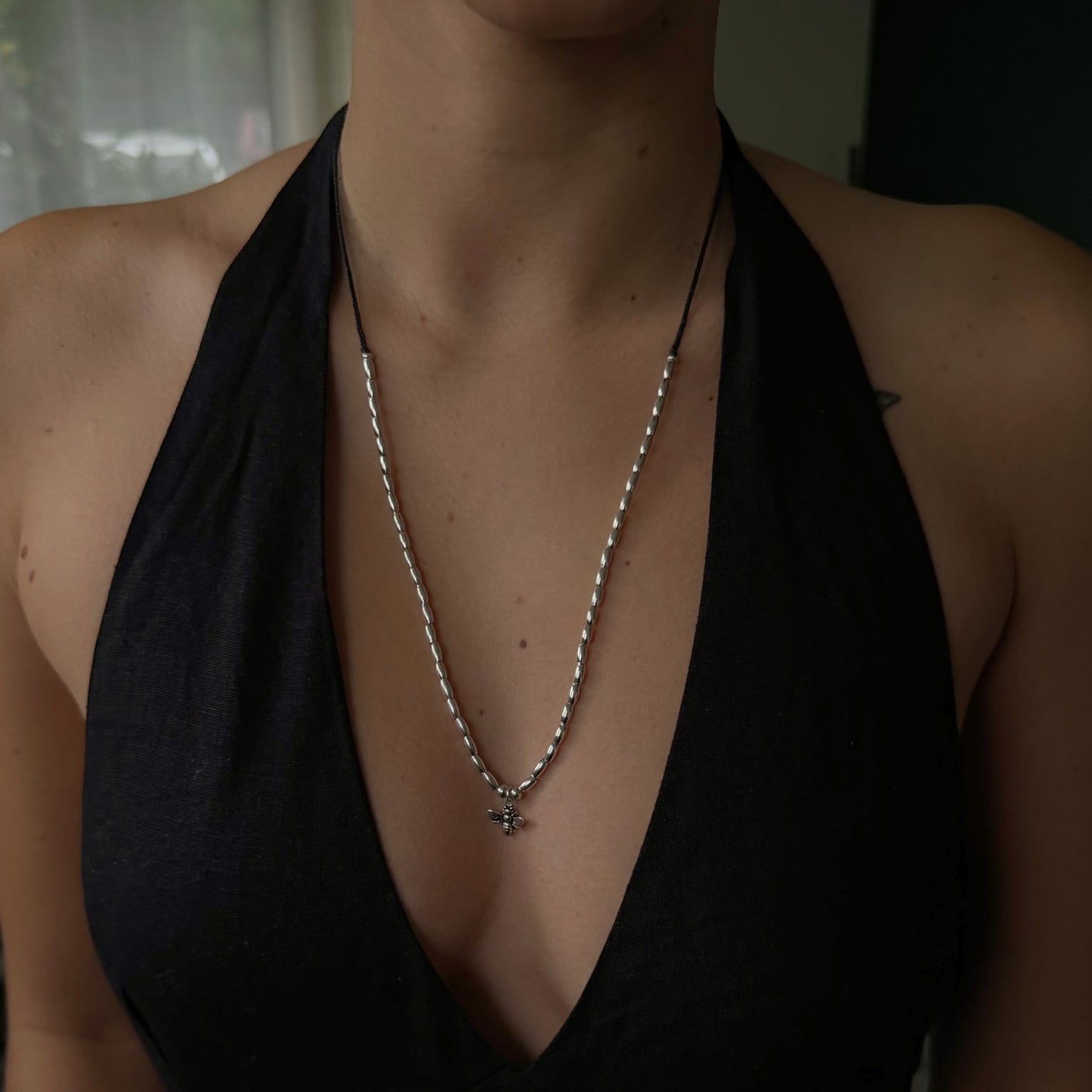 Person wearing a black halter top and a necklace with a pendant.
