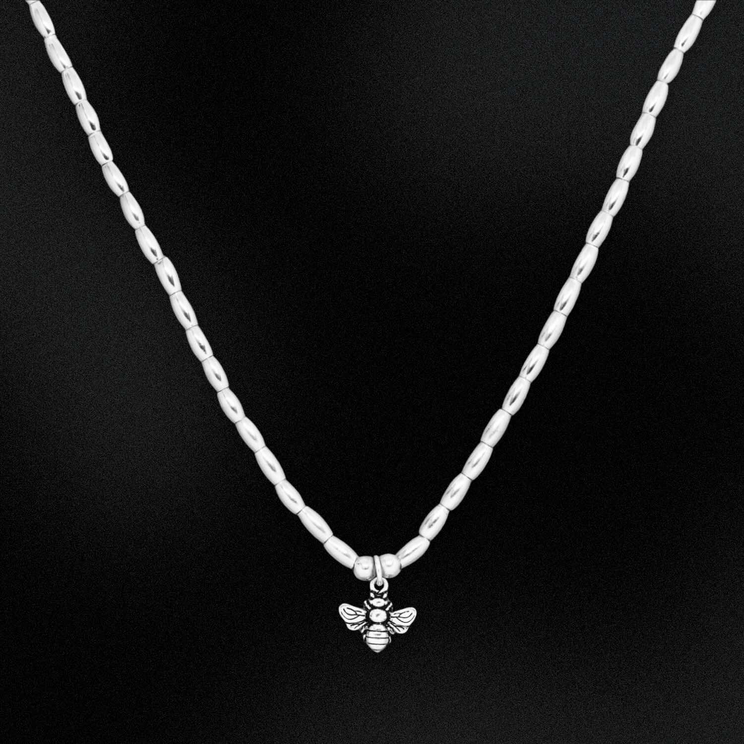 Silver chain necklace with a bee pendant on a black background