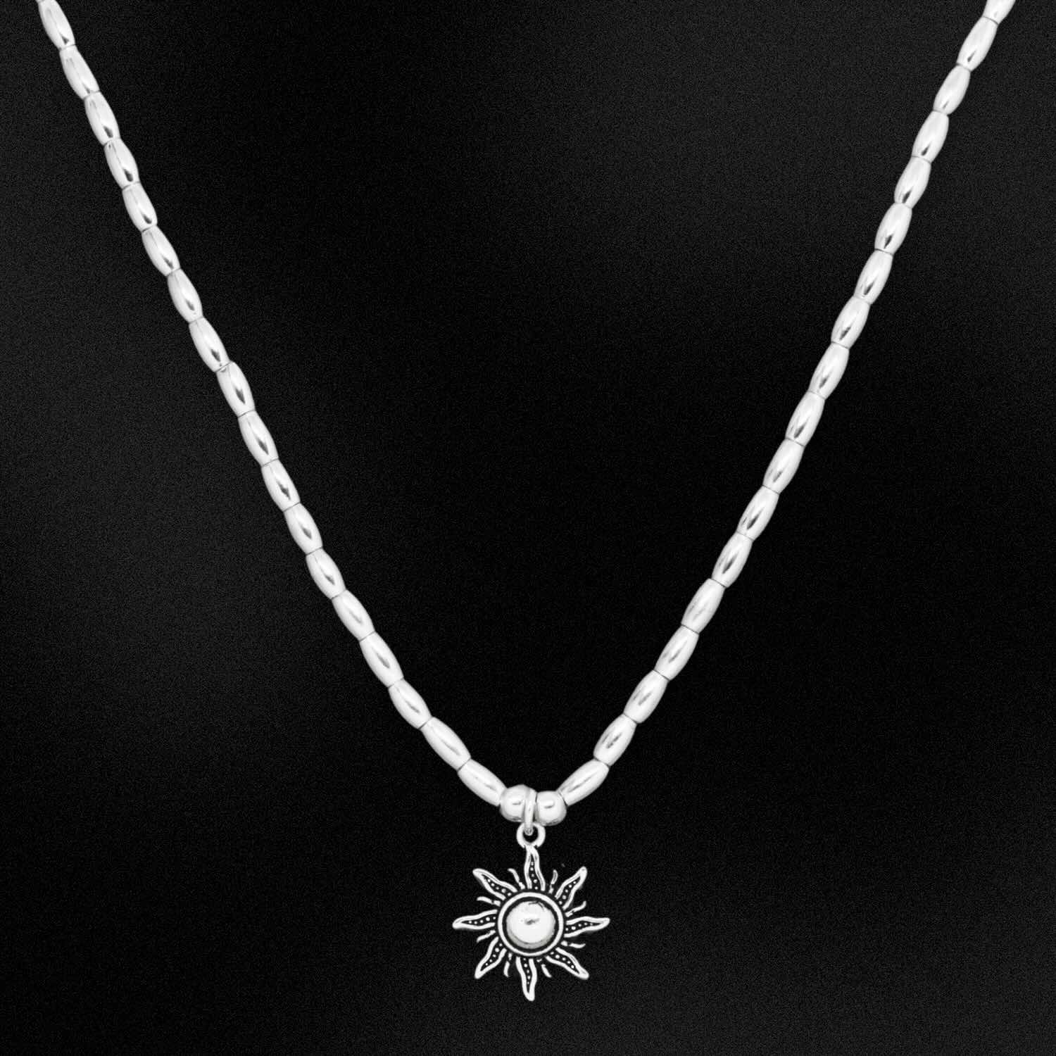Silver necklace with a sun pendant on a black background