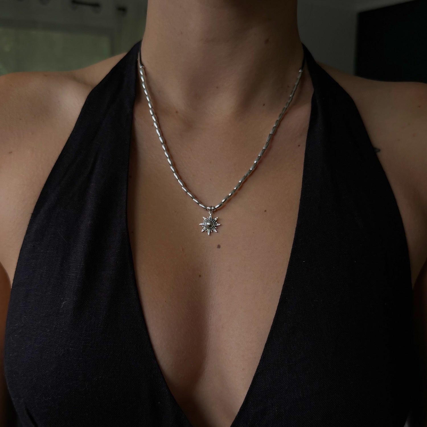 Person wearing a black top with a necklace featuring a star-shaped pendant.