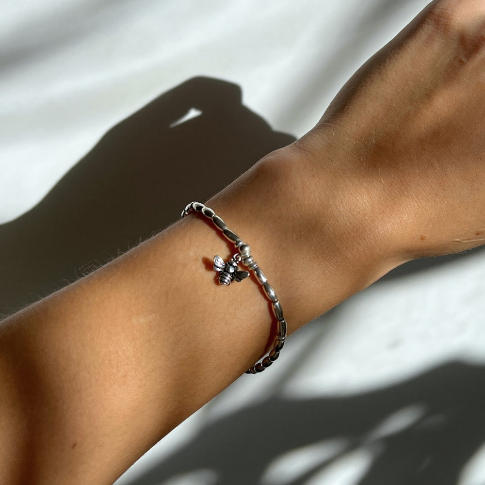 Embrace the beauty and energy of nature with our Bee Charm Sterling Silver Beaded Bracelet. Handcrafted with sterling silver beads on a durable wax string, this bracelet showcases a charming bee motif at its center. Perfect for adding a touch of whimsy and elegance to any outfit. Buzz into style with this charming bracelet!