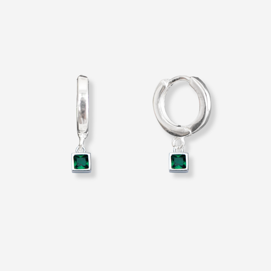 Silver hoop earrings with green gemstones on a white background