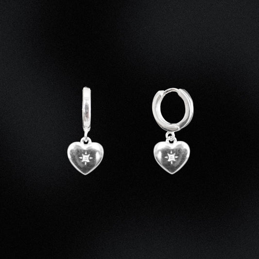 Silver heart-shaped earrings on a black background