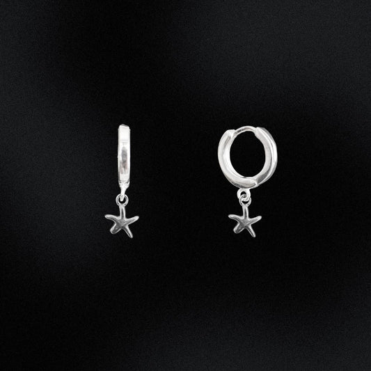 Silver hoop earrings with starfish charms on a black background