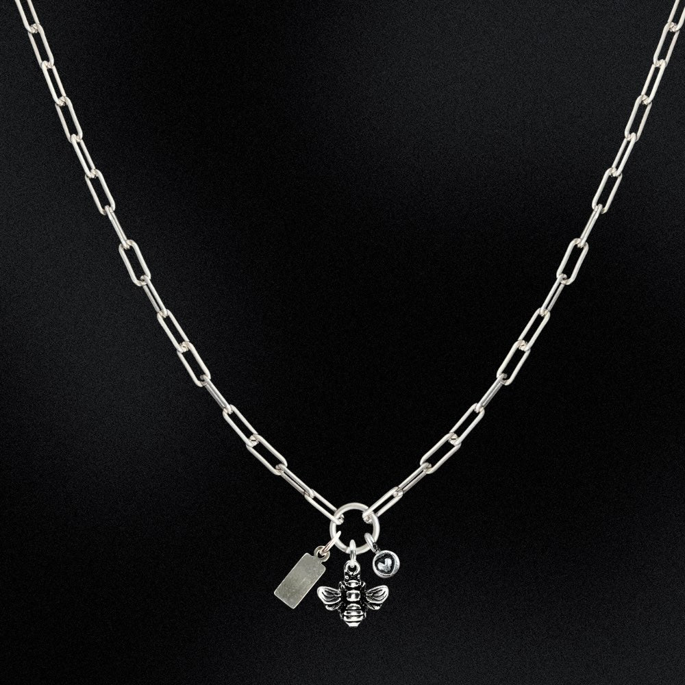 Silver chain necklace with a bee charm on a black background