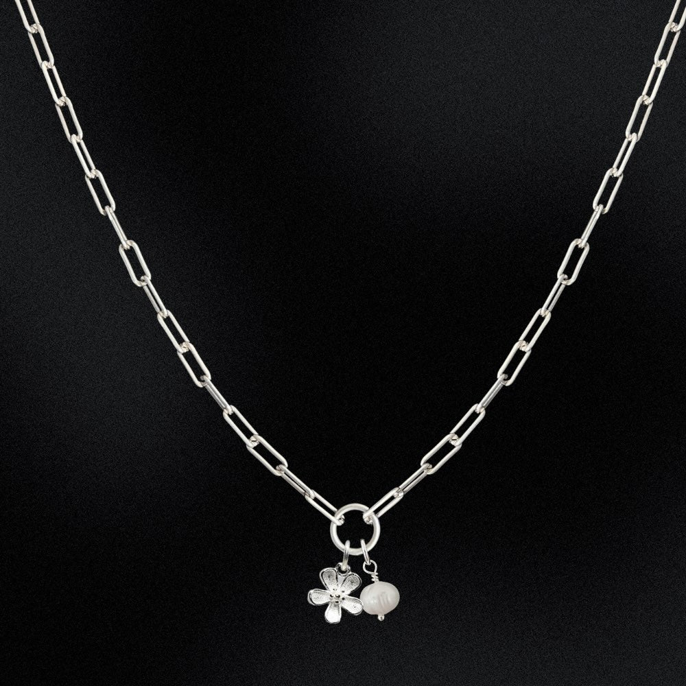 Silver necklace with a floral pendant on a black background
