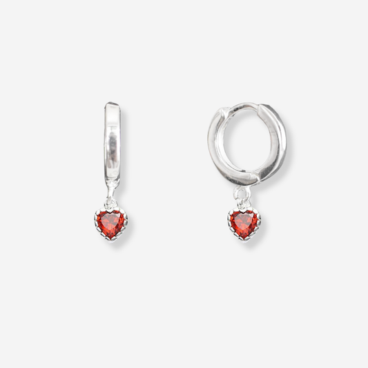 Silver hoop earrings with red heart-shaped stones on a white background