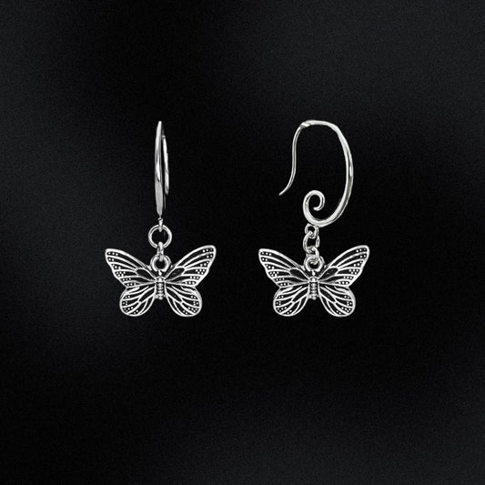 Butterfly-shaped silver earrings on a black background