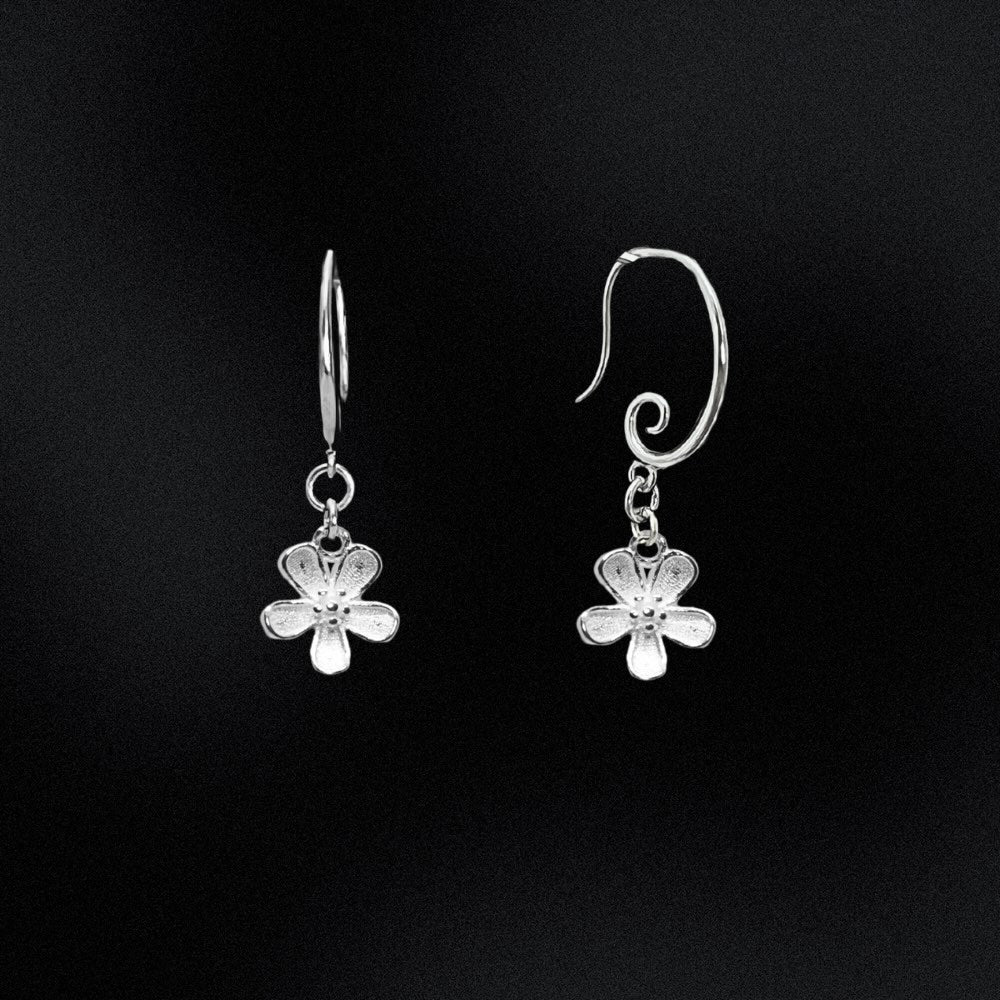 Silver flower-shaped earrings on a black background
