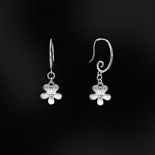 Silver flower-shaped earrings on a black background