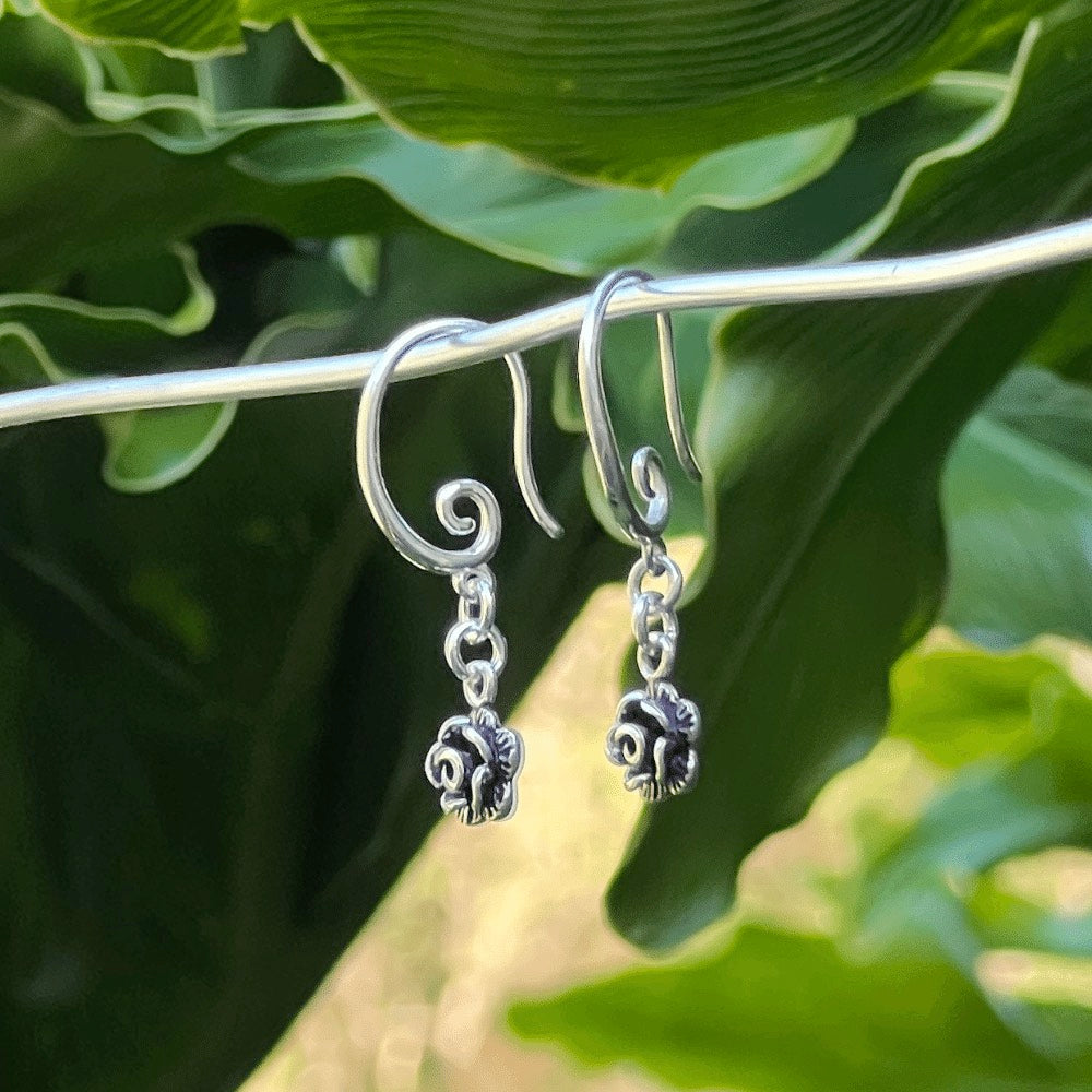 Featuring a gorgeous swirl earring hook that delicately and securely attaches to your ear, these earrings are perfect for any occasion. But what truly makes them unique is the intricately designed Black and Silver rose flower charm that dangles from the bottom of each earring.