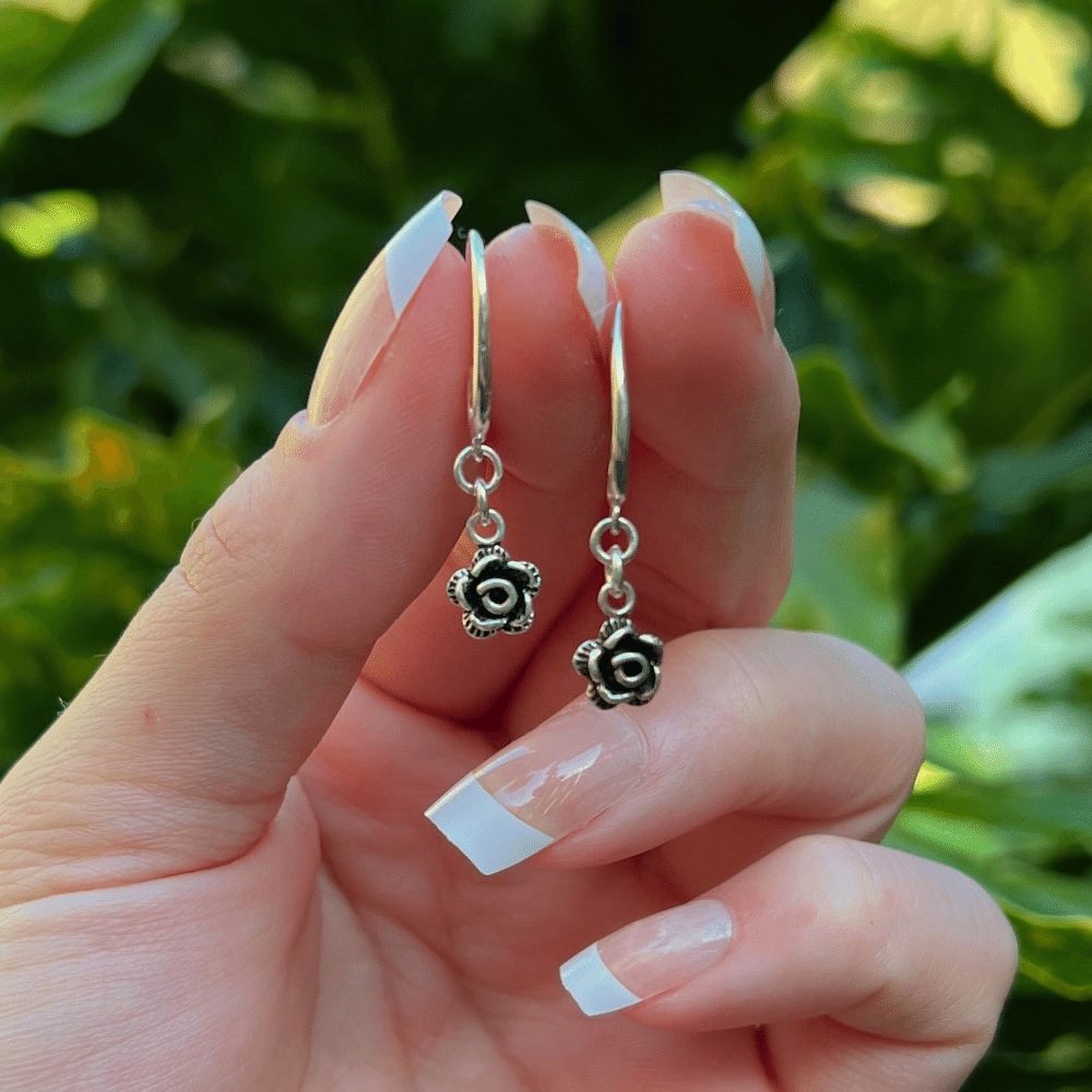 Featuring a gorgeous swirl earring hook that delicately and securely attaches to your ear, these earrings are perfect for any occasion. But what truly makes them unique is the intricately designed Black and Silver rose flower charm that dangles from the bottom of each earring.