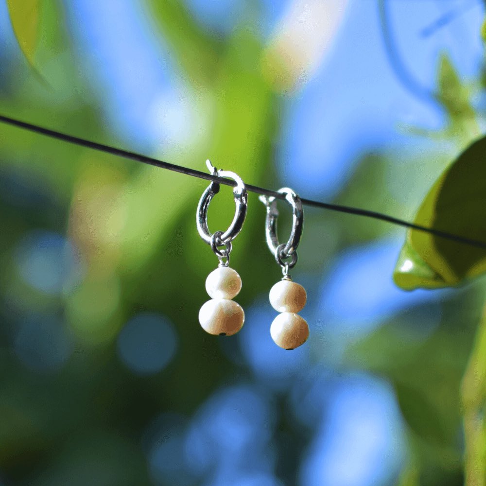 These hoop earrings feature two big, lustrous freshwater pearls that dangle gracefully from the hoops. The pearls are expertly selected for their perfect round shape, lustrous shine, and creamy white color. The result is a classic and elegant look that will elevate any outfit to the next level.