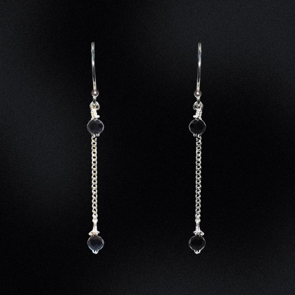 These earrings are a stunning addition to any wardrobe, perfect for adding a touch of elegance to any outfit. The earrings are made from high-quality sterling silver, ensuring their durability and long-lasting beauty. The earrings feature faceted glass rondelle black beads that are hung from a curb chain. The black beads are absolutely striking against the sterling silver and the chain adds a unique and modern twist to these timeless earrings.