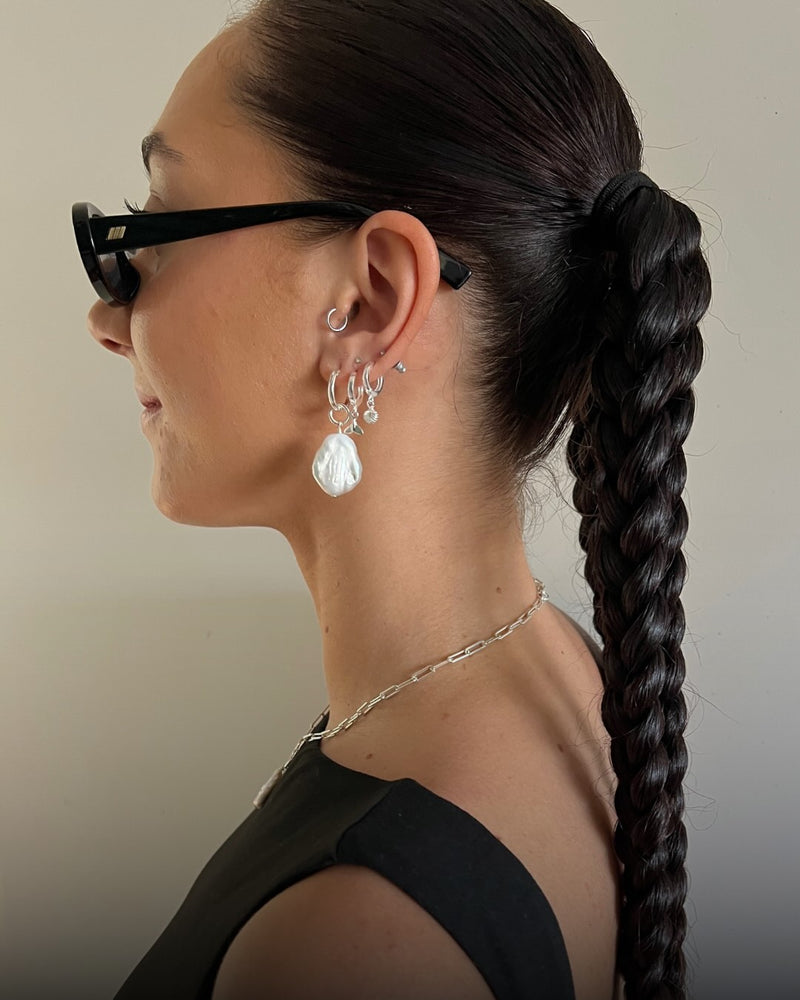 Woman wearing glasses with a side profile, focusing on earrings and hair.