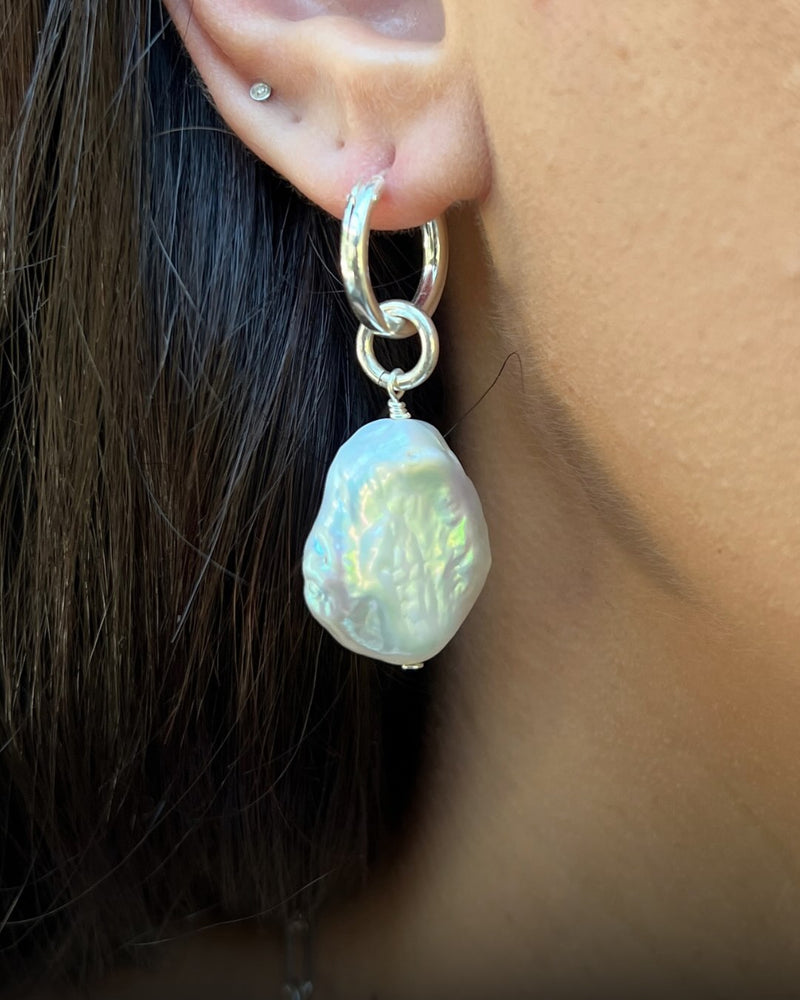 Pearl earring worn on an ear with a blurred background