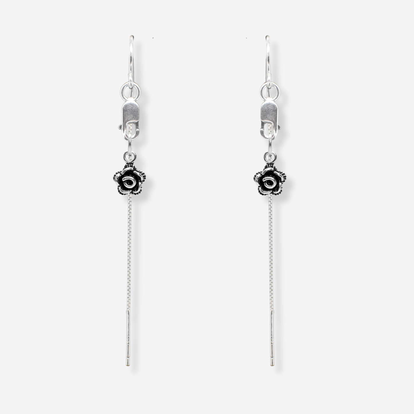 Pair of silver earrings with floral charms on a white background