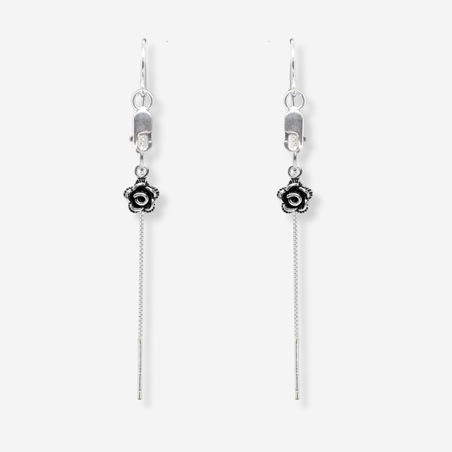 Pair of silver earrings with floral charms on a white background