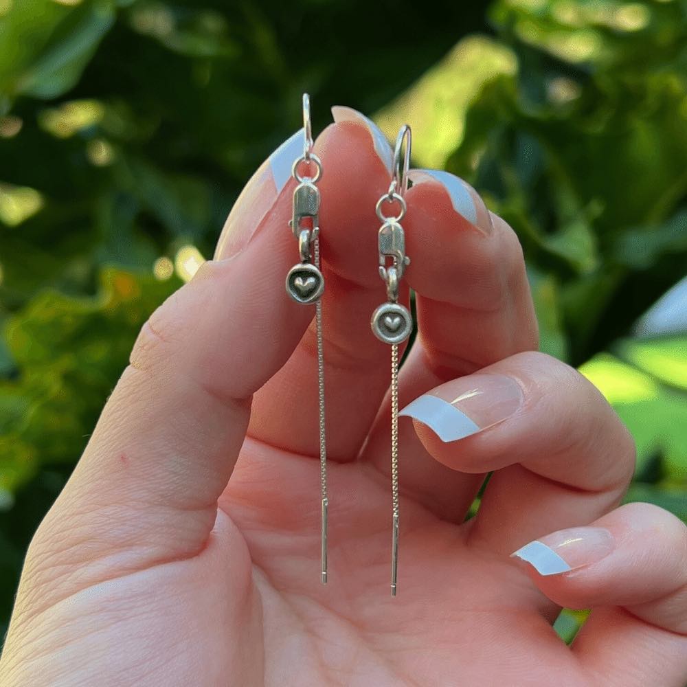 These earrings are a true embodiment of love, featuring delicate tiny heart charms that will dangle gracefully from your earlobes. The heart charms are carefully crafted with pure sterling silver, giving the earrings a shiny, high-quality finish that is both stunning and timeless. The threader style of the earrings is unique and easy to wear. The earrings are designed with a lobster clasp, which allows for easy and secure attachment.