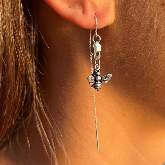 Let it Bee - Silver Thread Earrings are the perfect addition to any wardrobe. Crafted from sterling silver, they feature a delicate bee charm, suspended from a lobster clasp and lightweight threaders, making them a timeless and elegant choice.  They are comfortable to wear and guaranteed to start a conversation. Add a modern touch to your look with this stunning piece of jewellery that is perfect for everyday or a special night out.