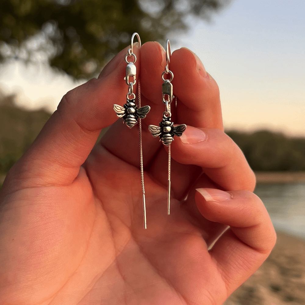 Let it Bee - Silver Thread Earrings are the perfect addition to any wardrobe. Crafted from sterling silver, they feature a delicate bee charm, suspended from a lobster clasp and lightweight threaders, making them a timeless and elegant choice.  They are comfortable to wear and guaranteed to start a conversation. Add a modern touch to your look with this stunning piece of jewellery that is perfect for everyday or a special night out.
