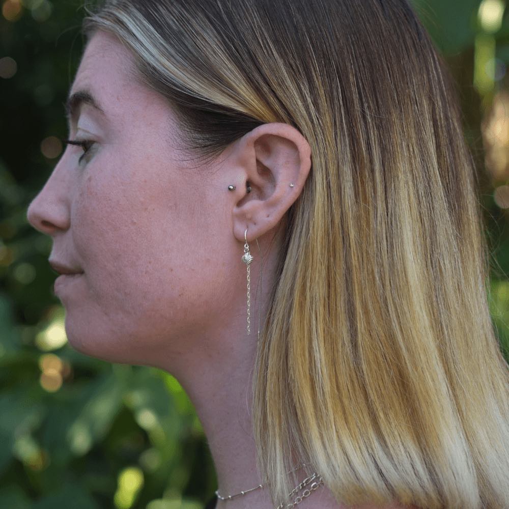 Take a stroll on the beachy side with these adorable Sea Shell & Chain Threader Earrings. These threaders add the perfect touch of whimsy to any outfit, and they're sure to lead to an ocean of compliments! Who knew shells and chains could be so stylish?!  These earrings are lightweight and easy to wear, making them perfect for those who are always on the go. Handmade from Sterling Silver.