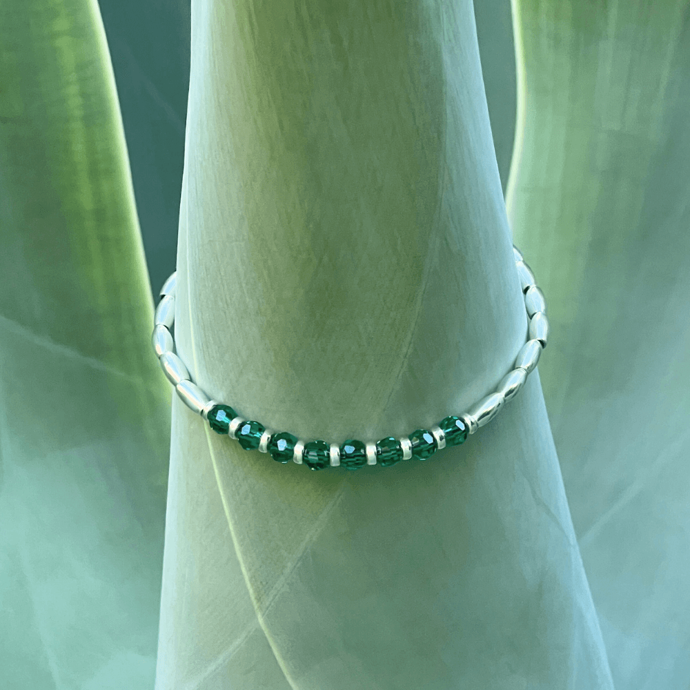 Introducing the Emerald Essence Silver Beaded Bracelet - the perfect accessory to complete any outfit. The centre detail of the bracelet features stunning faceted glass rondelle green beads that catch the light and sparkle brilliantly. Surrounding these gems are delicate silver beads, adding a touch of sophistication and elegance to the design.