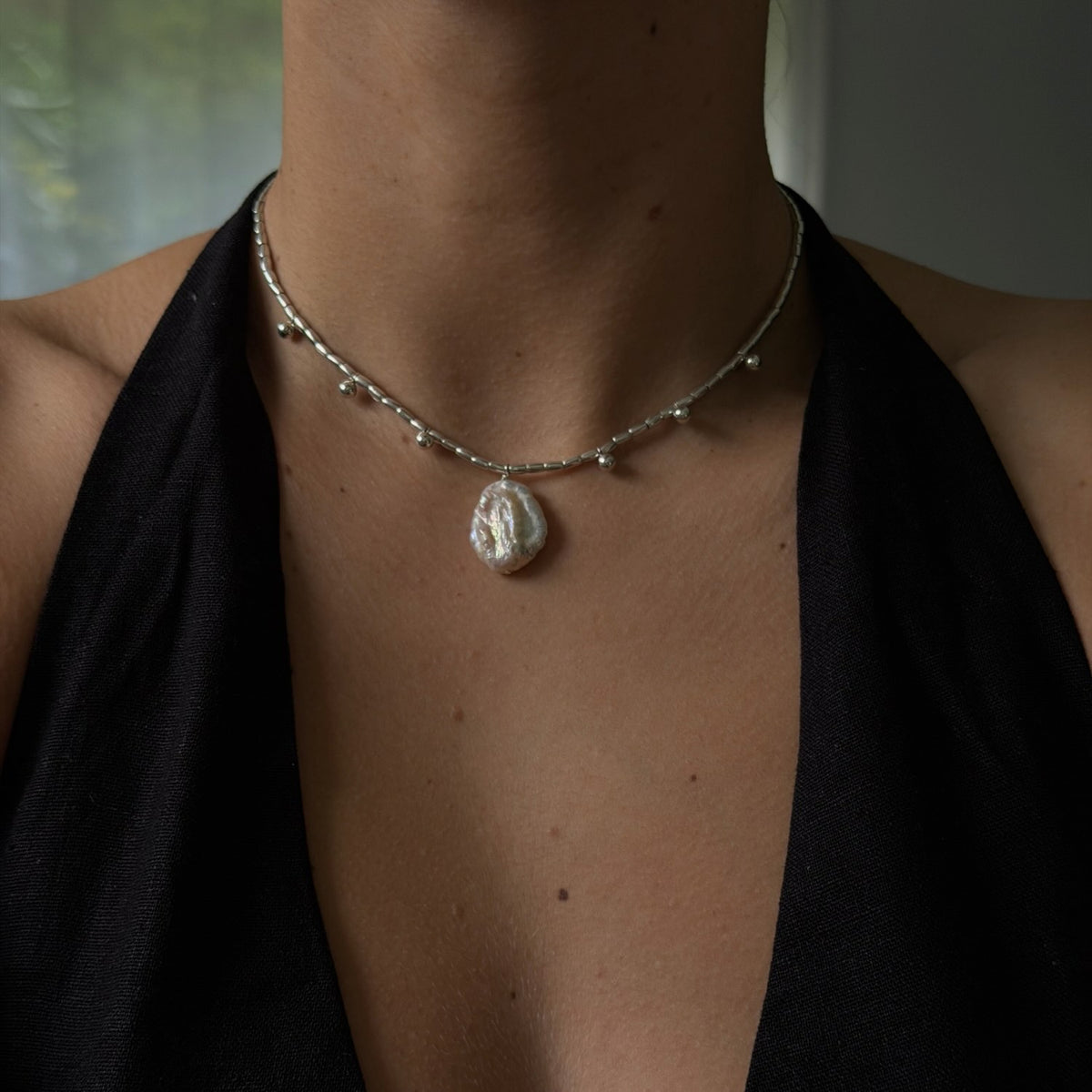 Necklace with a pendant worn by a person against a neutral background