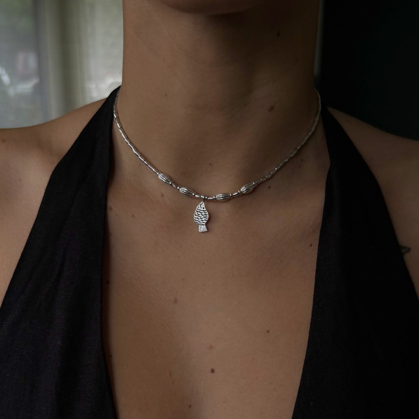 Necklace with a pendant worn by a person against a neutral background