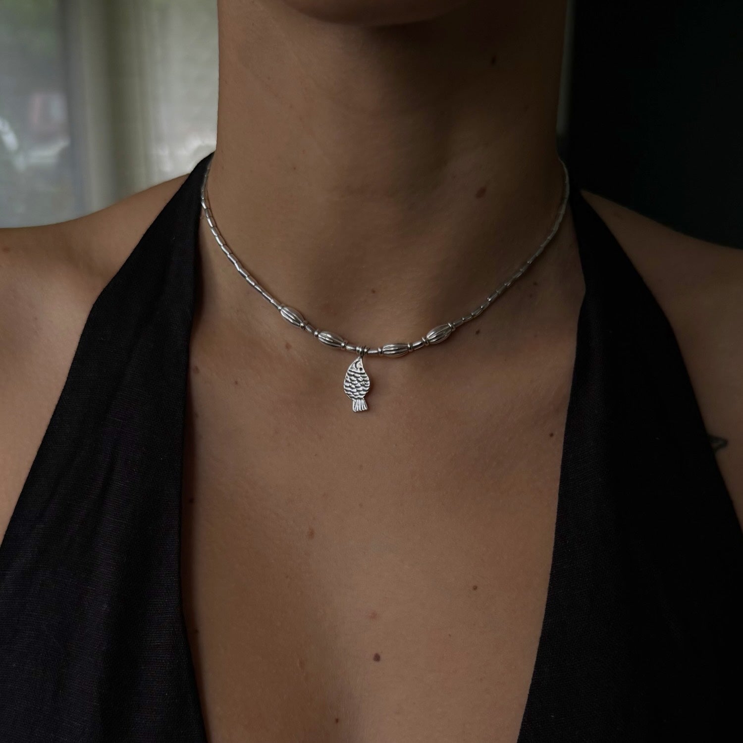 Necklace with a pendant worn by a person against a neutral background
