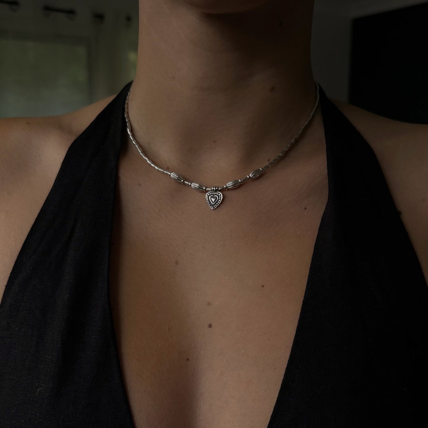 Necklace with a heart pendant worn by a person against a dark background