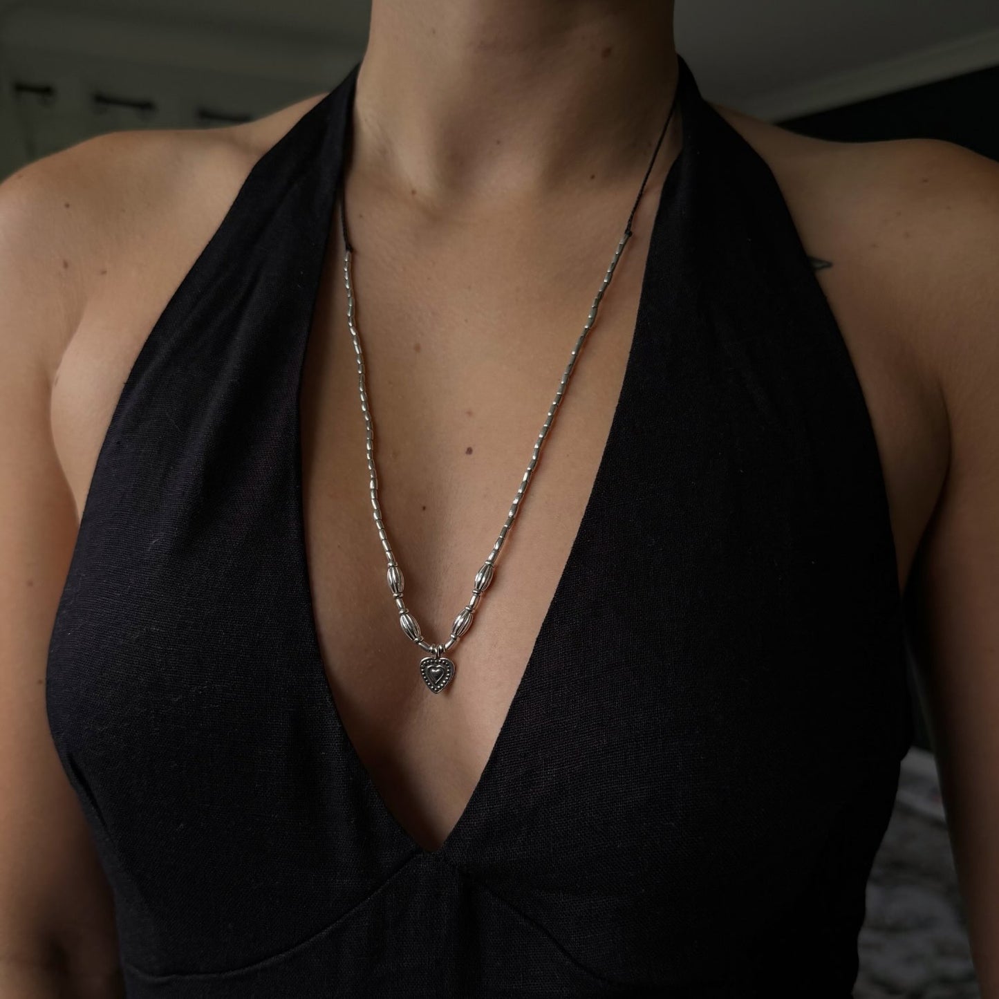 Person wearing a black top with a deep neckline and a necklace.